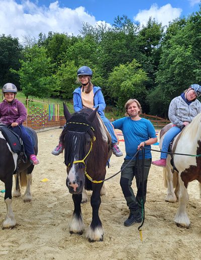 Vier Menschen, davon drei Reiterinnen mit Helm