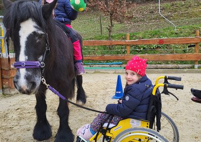 Zwei lächelnde Mädchen interagieren auf einem Reitplatz