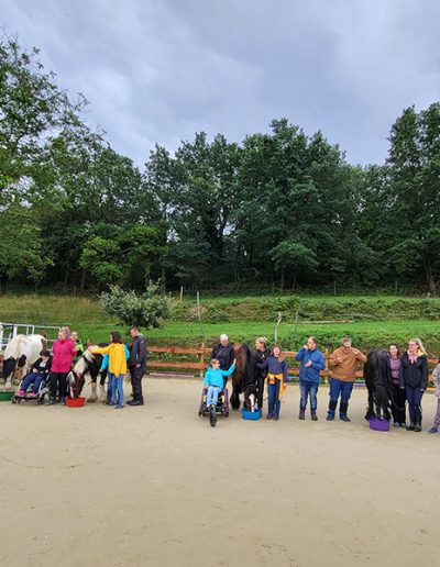 Gruppe von Menschen mit Pferden auf dem Reitplatz