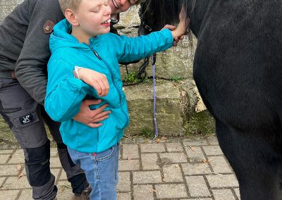 Junge streichelt Pferd am Hals