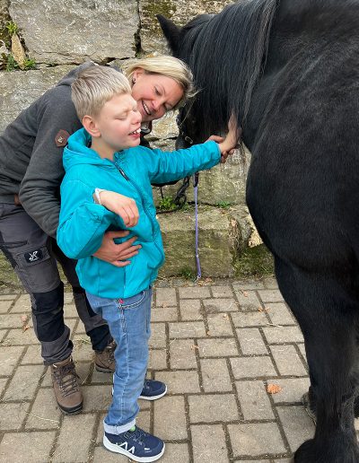 Junge streichelt Pferd am Hals